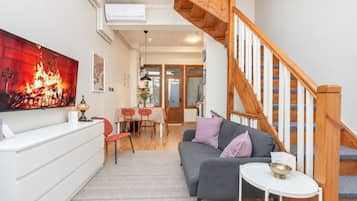 A modern living room with a grey sofa, a white coffee table, and a wooden staircase.