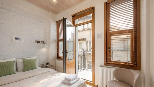 A bedroom with a bed, a chair, a radiator, and a window with blinds.