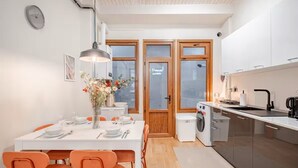 A compact kitchen with a dining area, featuring a washing machine, a sink, and a dining table with chairs.