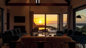 Una sala de estar moderna con un ventanal grande que ofrece una vista panorámica del atardecer.