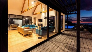 Un espacio moderno para relajarse con terraza de madera, grandes puertas de vidrio y una piscina visible a través de las ventanas.