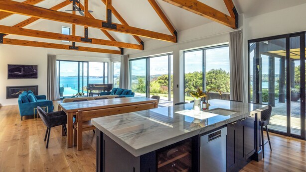 Una cocina amplia con una isla grande, vigas de madera y ventanas que ofrecen vistas al exterior.