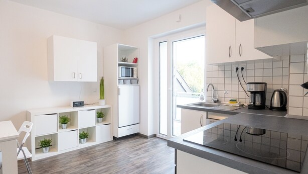 A modern kitchen with white cabinets, a built-in microwave, and a black countertop.
