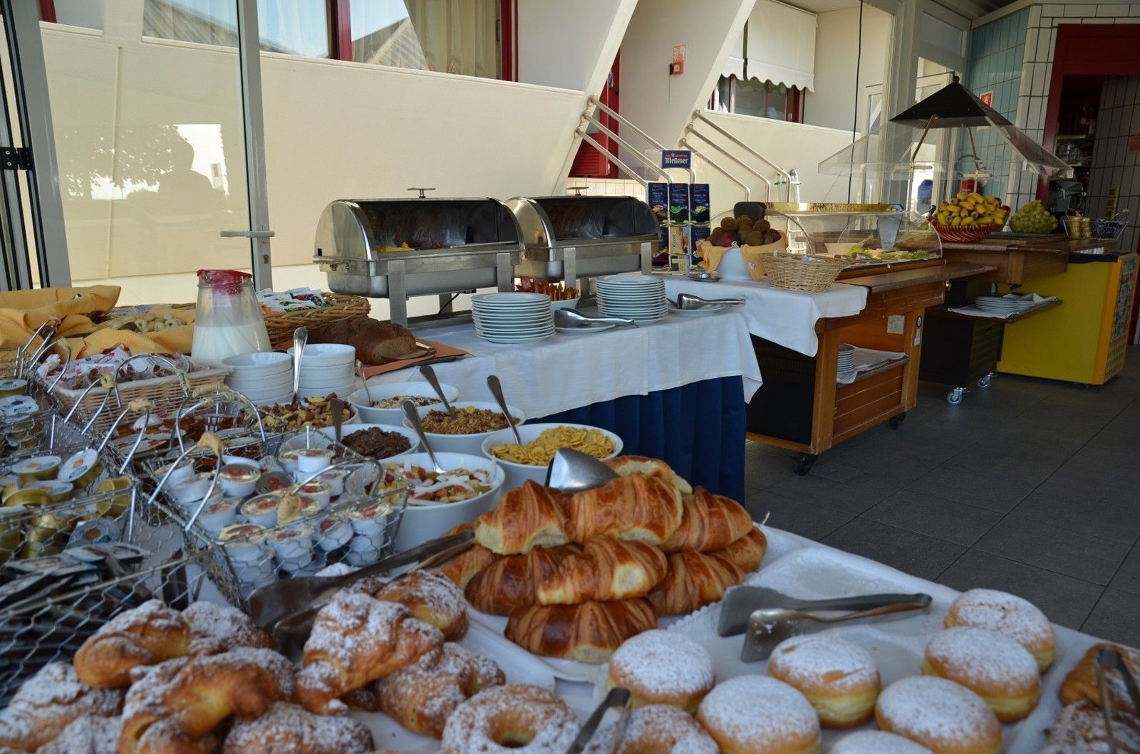 Un buffet proposant une variété de plats, notamment des pâtisseries, du pain et des condiments.