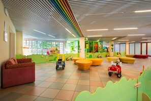 Zona de juegos infantiles con muebles coloridos, una estructura de juego y un tren de juguete.
