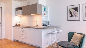 A modern kitchen with white cabinetry, a built-in oven, and a bar area with stools.