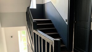 Eine Treppe mit Holzwegen und schwarzen Geländern, die zu einer Tür führt.