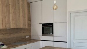 Eine moderne Küche mit Holzausstattung, einer zentralen Kochinsel, Hängeleuchten und einem Einbauofen.