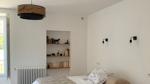 Ein Schlafzimmer mit Bett, Heizkörper, Bücherregal und einer Pendelleuchte.