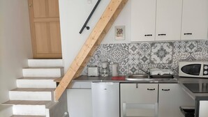 A kitchen with white cabinets, a microwave, a toaster, and a coffee maker. There is a wooden staircase leading to another room. - Gite in charming winegrowing village, twenty minutes from Carcassonne. (Comigne)