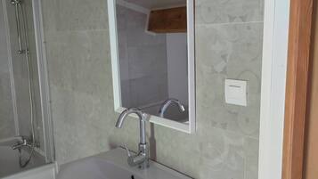 A bathroom with a white sink, a mirror, and a shower.