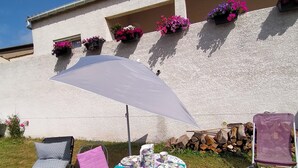 A patio area with a table set for two, a sun lounger, and a chair. - Gite in charming winegrowing village, twenty minutes from Carcassonne. (Comigne)