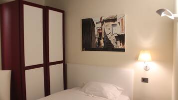 A hotel room with a bed, a nightstand, a lamp, and a painting on the wall.