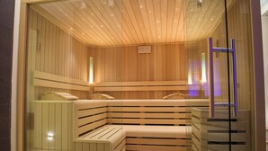 A sauna with wooden walls and benches, a glass door, and a clock on the wall. - Borgo Ospitale (Rotonda)
