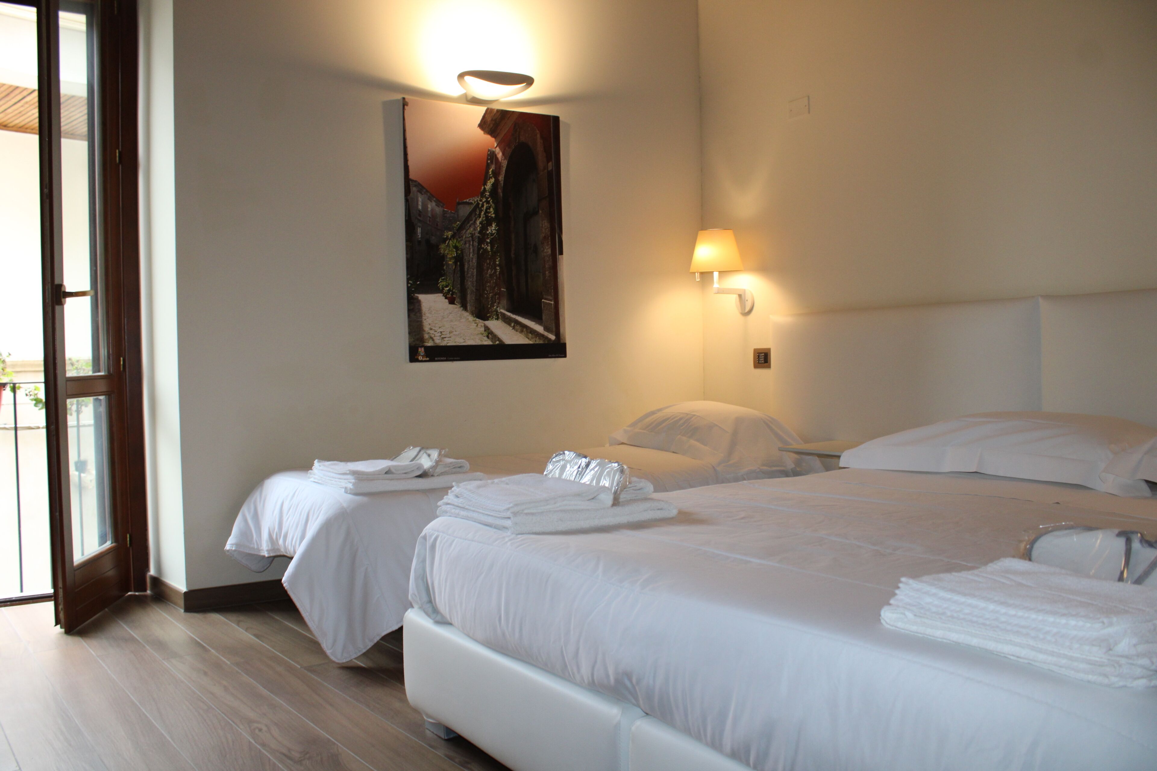 Habitación de hotel con dos camas, un ventanal grande y un cuadro colgado en la pared.