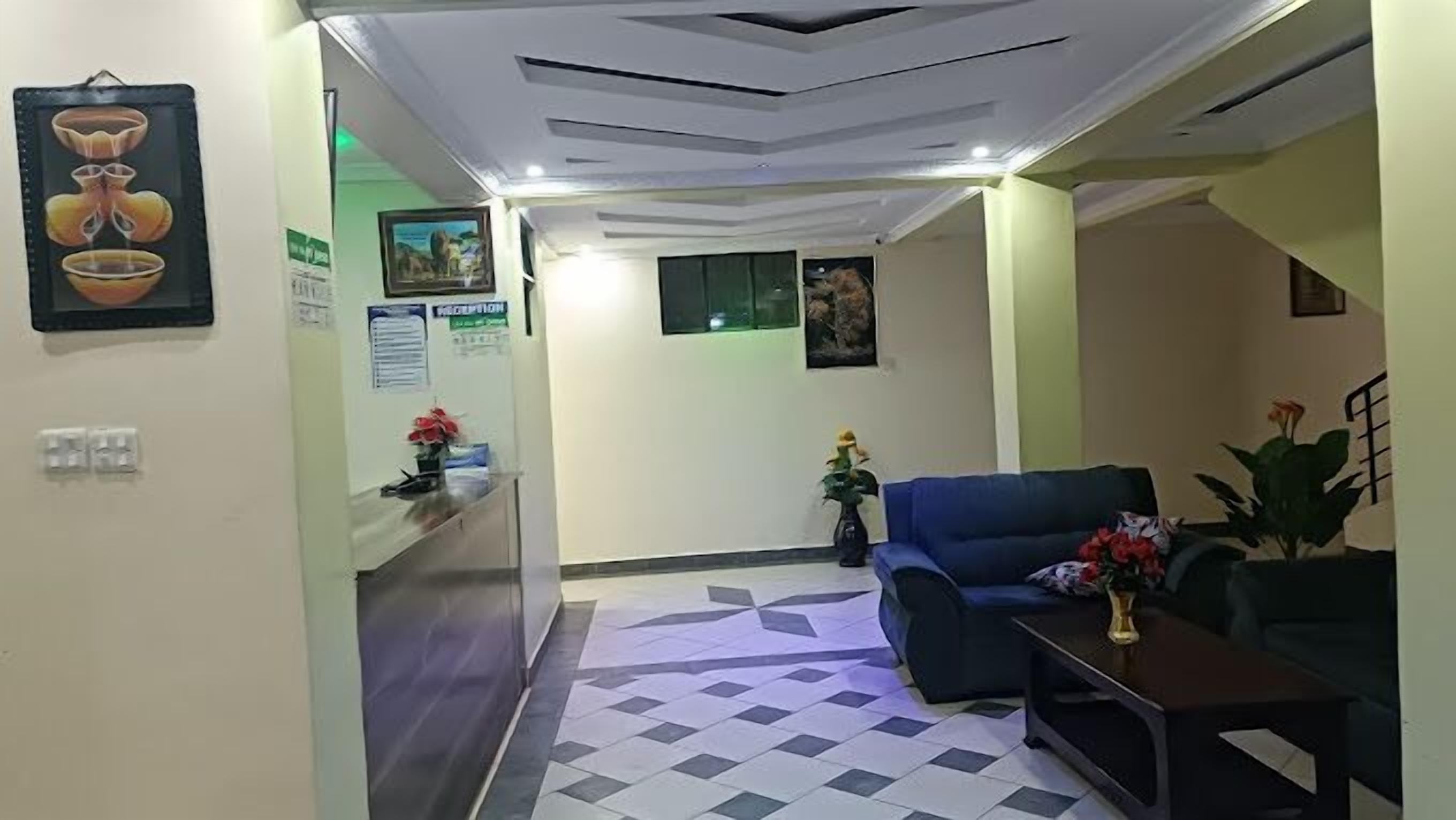 A reception area with a check-in counter, a blue sofa, and a small table with flowers.
