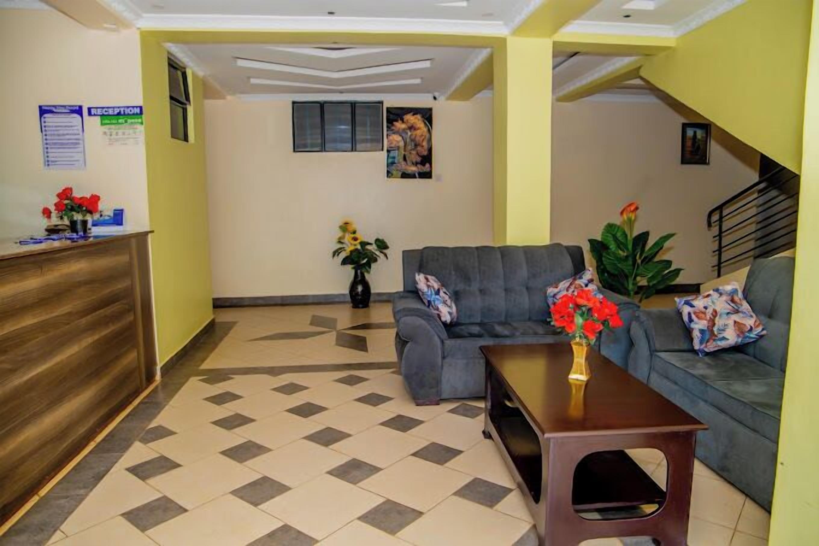 A reception area with a reception desk, a grey sofa, a coffee table, and a staircase.