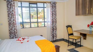 A hotel room with a bed, a desk, and a chair. - Happy Stay Resort Kisii (Kisii)