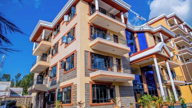 A multi-story hotel with balconies, large windows, and a clear sky. - Happy Stay Resort Kisii (Kisii)