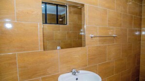 A bathroom with a white sink, a mirror, and a towel rack. - Happy Stay Resort Kisii (Kisii)