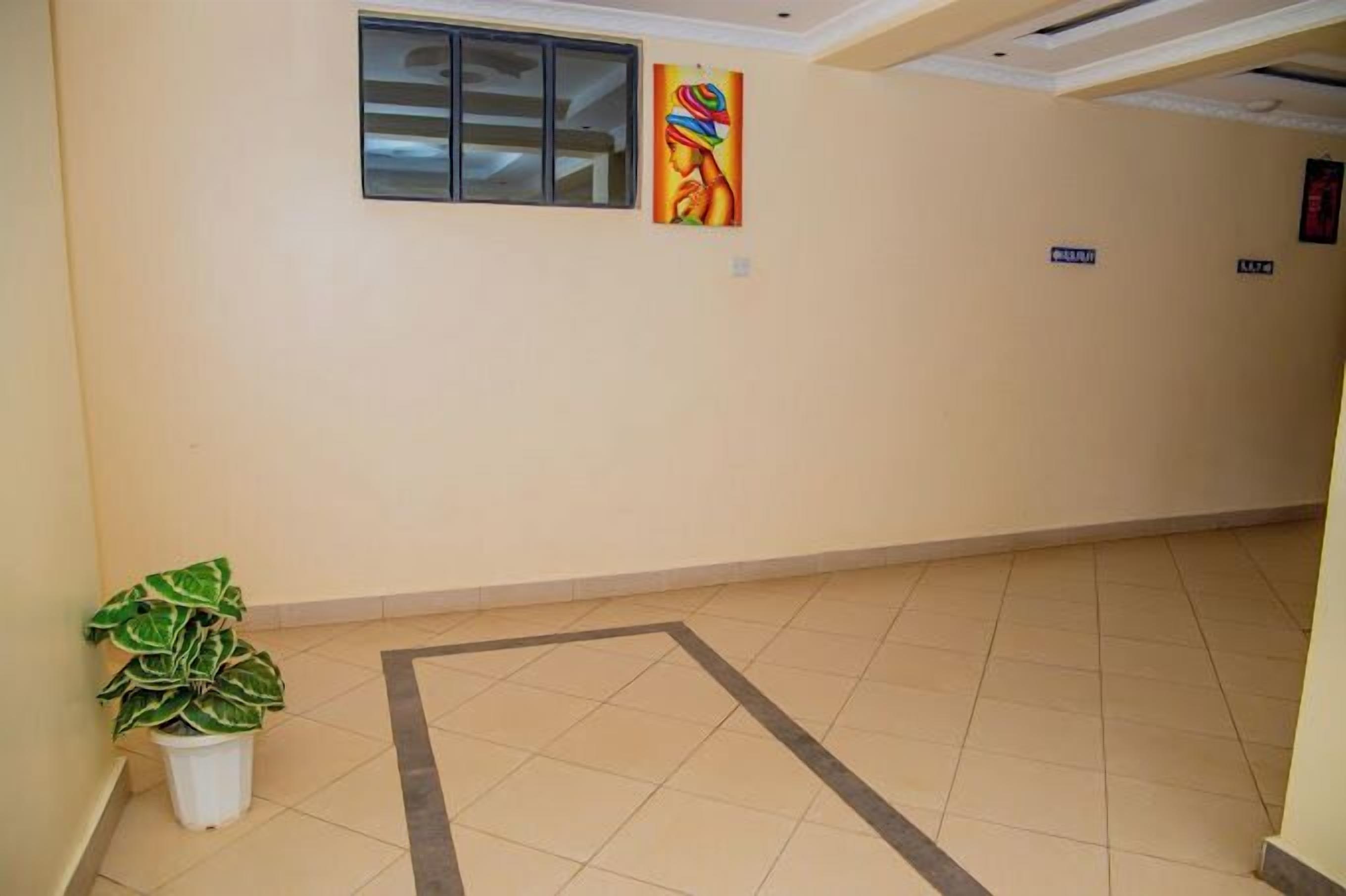 A hallway with a potted plant, a window, and a colorful painting on the wall.