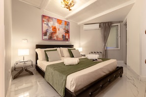 A modern bedroom with a large bed, a bedside table, a lamp, an air conditioning unit, and a painting on the wall. - Crispi 30: A Stylish Apartment (Roma)