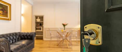Een moderne woonkamer met een zwarte leren bank, een eethoek met een glazen tafel en een zwarte deur met slot.