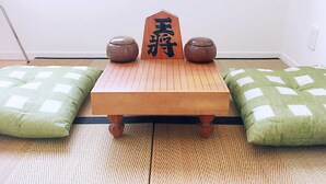 A tatami mat room with a low wooden table, two green cushions, and two ceramic bowls.
