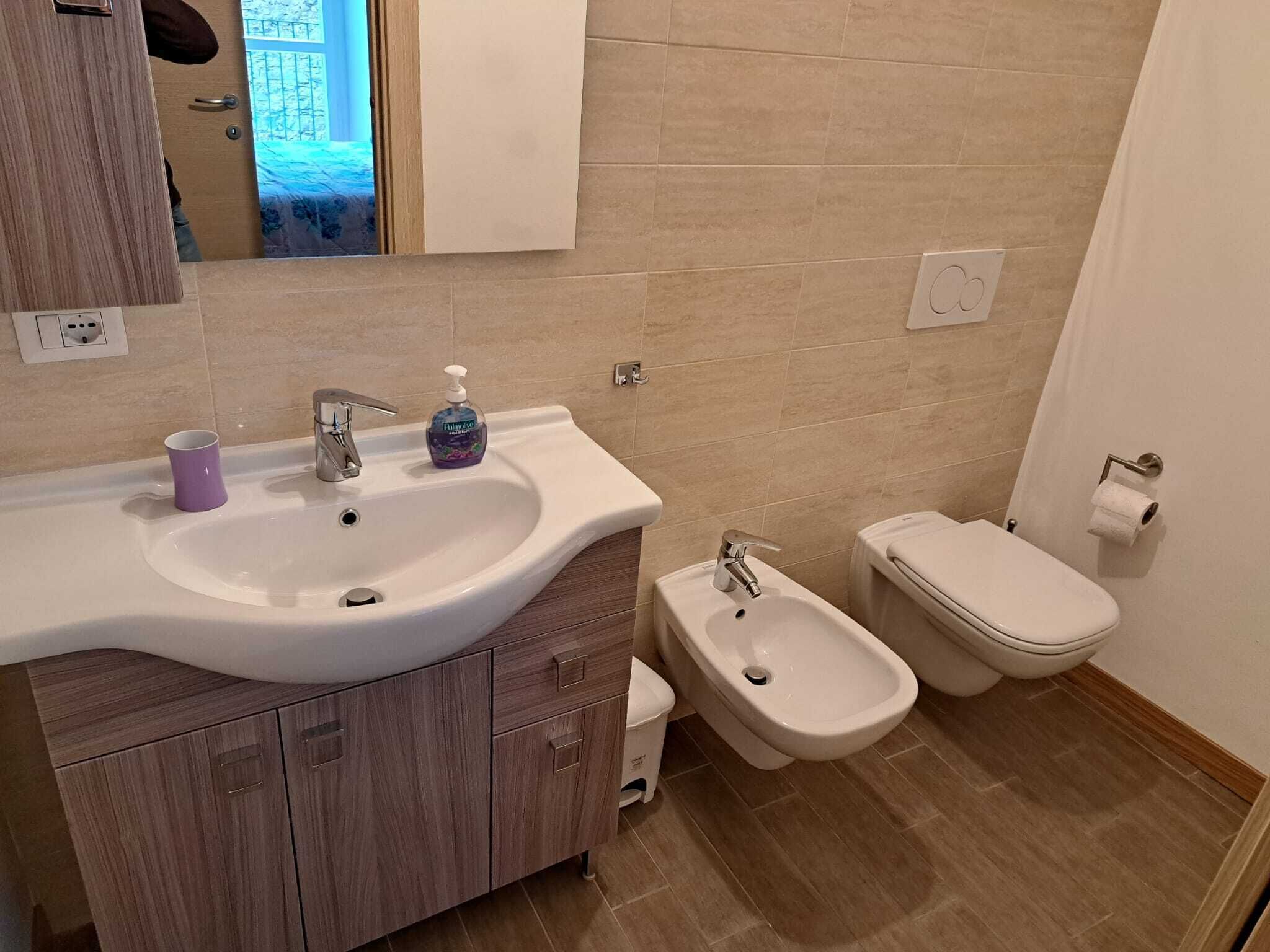 Un bagno con lavandino, bidet, wc e mobili in legno.