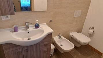 Un bagno con lavandino, bidet, wc e mobili in legno.