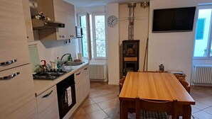 Una cucina funzionale con zona pranzo, piano cottura, lavello e un orologio appeso al muro.