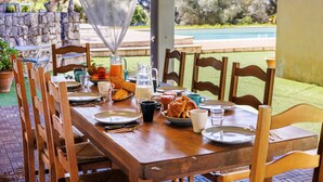 A wooden dining table set for breakfast with plates, cups, and a pitcher of orange juice.