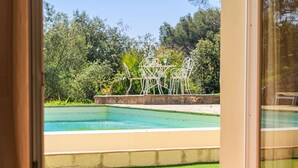 A room with a view of a swimming pool and outdoor seating area.