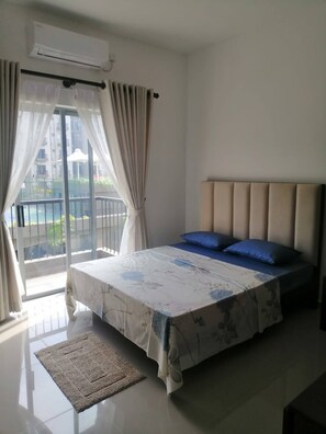 Un dormitorio con cama, cortinas, aire acondicionado y vistas al exterior.