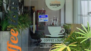 Ein Café mit Glastür, einem Schild, das auf Öffnungszeiten hinweist, und dem Logo des Cafés.