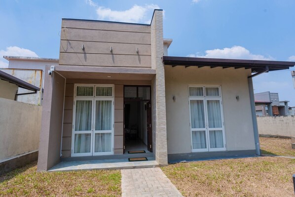 A modern two-story house with a flat roof, large windows, and a small front porch. - Green Retreat 2BR Hideout (Polgasowita)