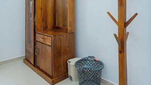 Eine Ecke mit einem Holzschrank, einem Kleiderhaken und einem Mülleimer.