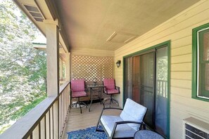 A covered porch with a table and chairs, a sliding glass door, and a view of trees.