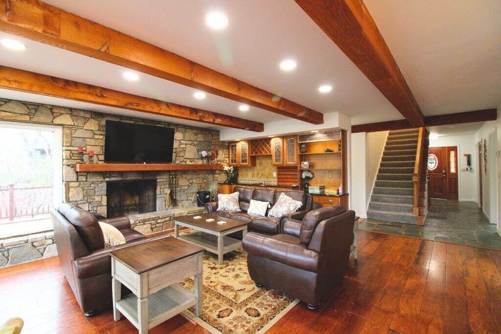 A living room with a stone fireplace, leather sofas, a coffee table, and a staircase.