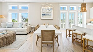 A spacious dining area with a large table and chairs, a sofa, and a wicker coffee table.