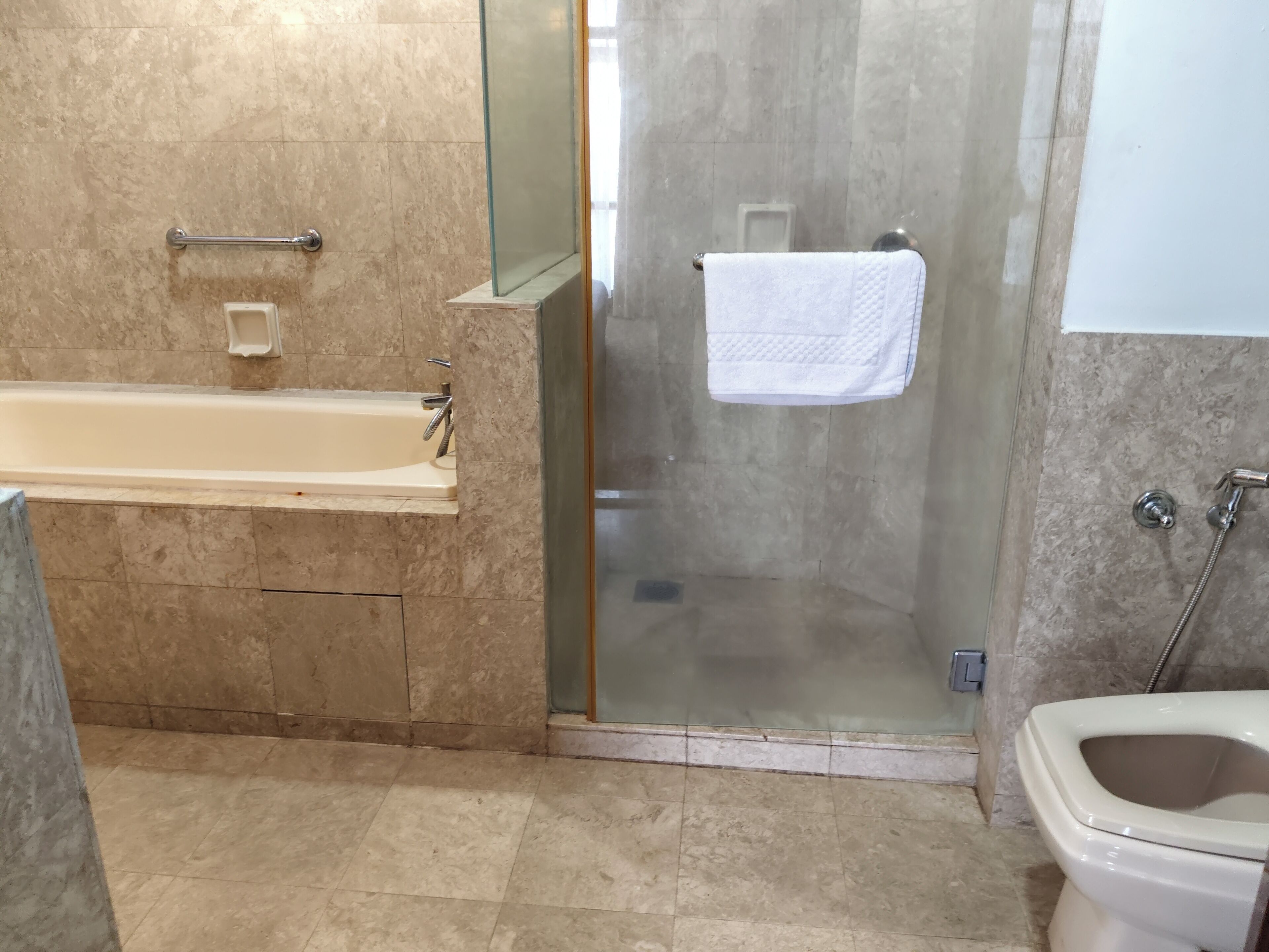 Une salle de bain avec une baignoire, une douche à parois de verre et des toilettes.