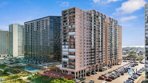 A high-rise building with multiple balconies, a parking lot, and a swimming pool area. - Ocean City Getaway | Capri 2BR w/ Ocean Views, Pool, Fitness Center (Ocean City)