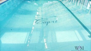 A swimming pool with the word "Capri" written on the floor. - Ocean City Getaway | Capri 2BR w/ Ocean Views, Pool, Fitness Center (Ocean City)