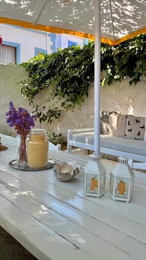 Een witte houten tafel met een kaars, een pot honing en twee lantaarns.
