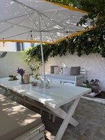 Une terrasse extérieure avec une table blanche, des bancs et un parasol.