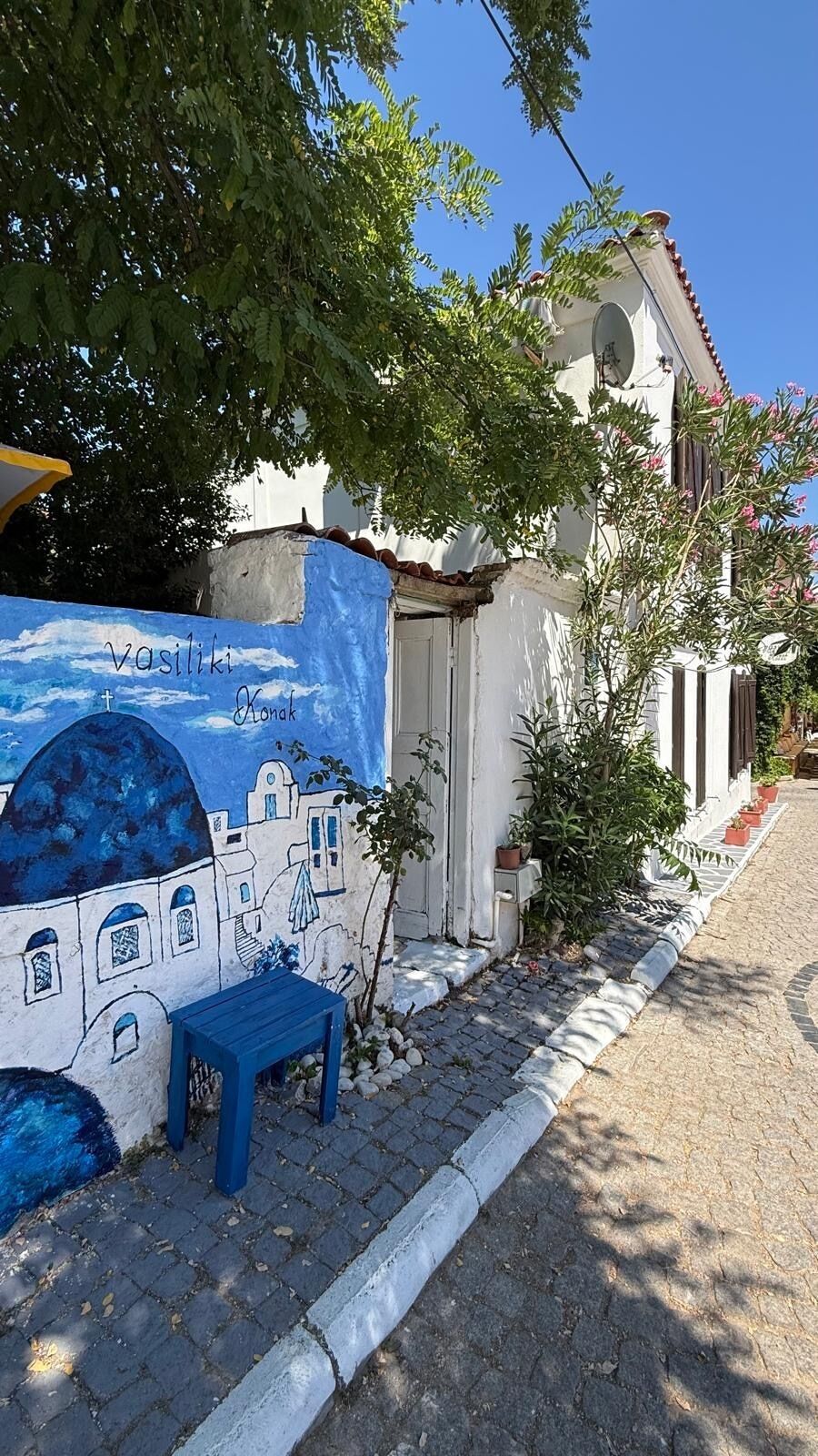 Een gebouw met een blauwe muurschildering, een tafeltje en een deur.