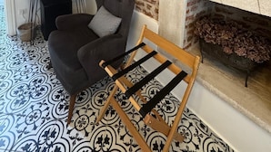 A room with a brick wall, a fireplace, a black armchair, a wooden bench, and patterned flooring. - Vasiliki Konak (Bozcaada)