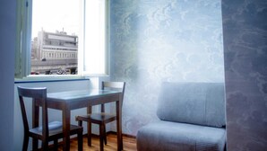A corner room with a window, a table, and a chair.