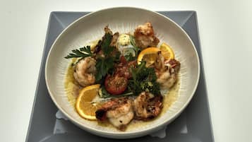 A plate of food with shrimp, lemon, and herbs.