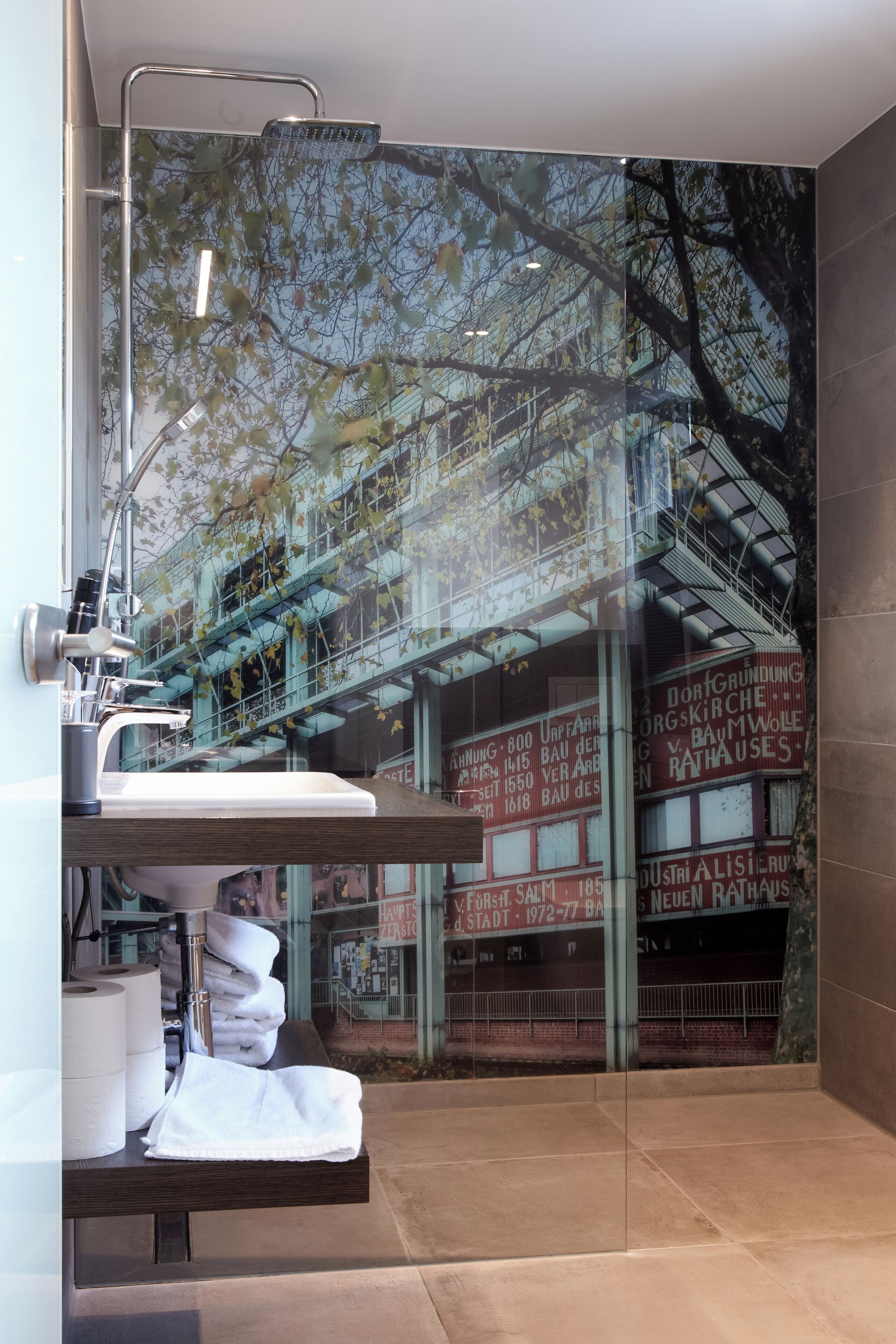 A bathroom with a large window, a sink, and a towel rack.